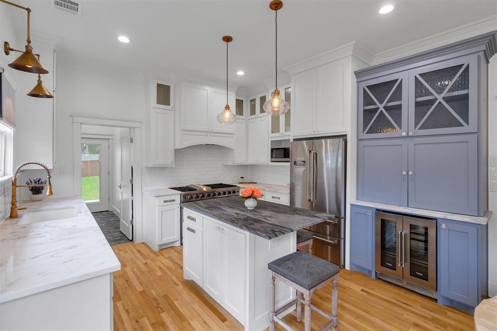 5727 Victor Street Dallas, TX 75214 - Photo 17 of 40 a kitchen with kitchen island a stove a refrigerator and a sink with wooden floor