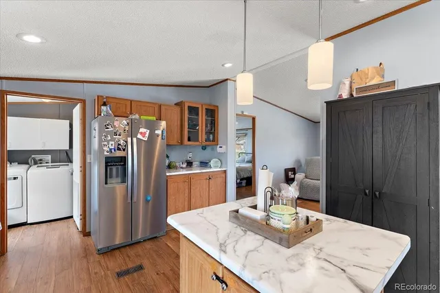 a kitchen with stainless steel appliances kitchen island granite countertop a refrigerator a stove and a wooden floors