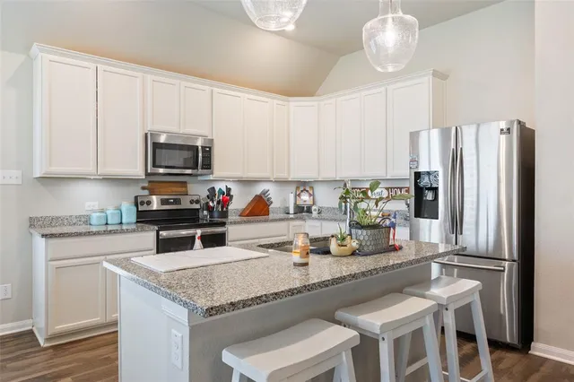 a kitchen with granite countertop a refrigerator stove and microwave