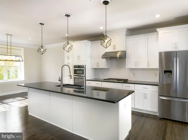 a kitchen with stainless steel appliances granite countertop a sink a stove a refrigerator and island with wooden floor