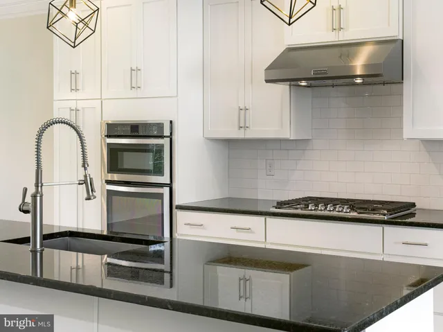 a kitchen with granite countertop a sink a stove and cabinets