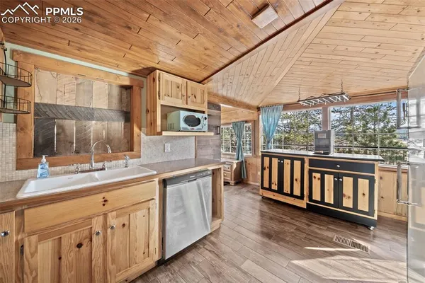 a large white kitchen with kitchen island a large window a sink and stainless steel appliances