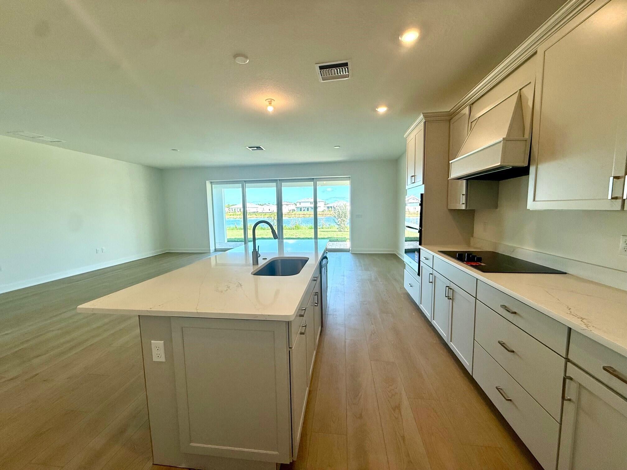 4340 Southwest Cornerstone Way, Unit WHITESTONE 136 Stuart, FL 34997 - Photo 6 of 34 a large kitchen with kitchen island a sink stainless steel appliances wooden floor and cabinets