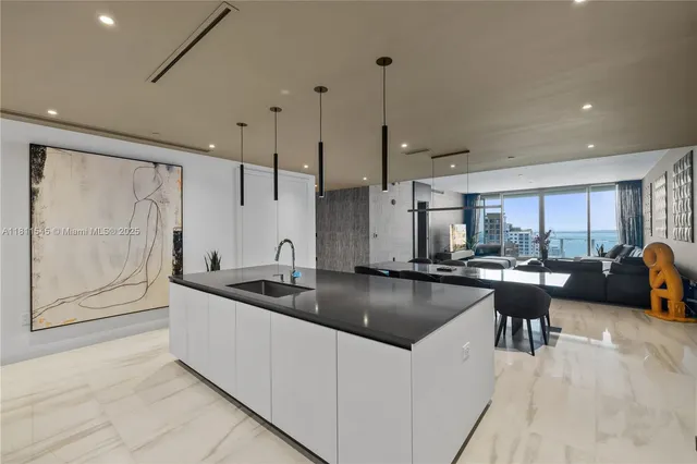 a large white kitchen with stainless steel appliances kitchen island a large counter top and a refrigerator