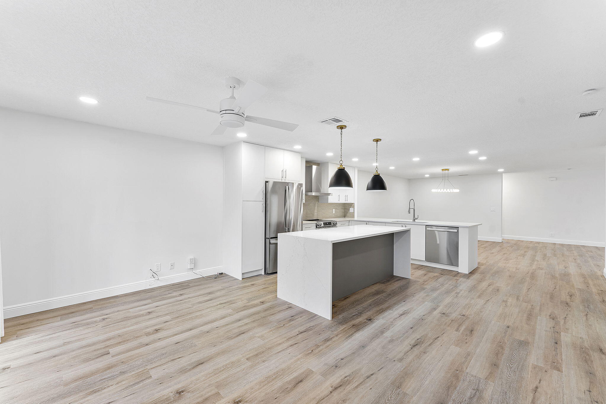 9180 Pine Springs Drive Boca Raton, FL 33428 - Photo 9 of 29 a large white kitchen with a large counter top a sink stainless steel appliances and cabinets