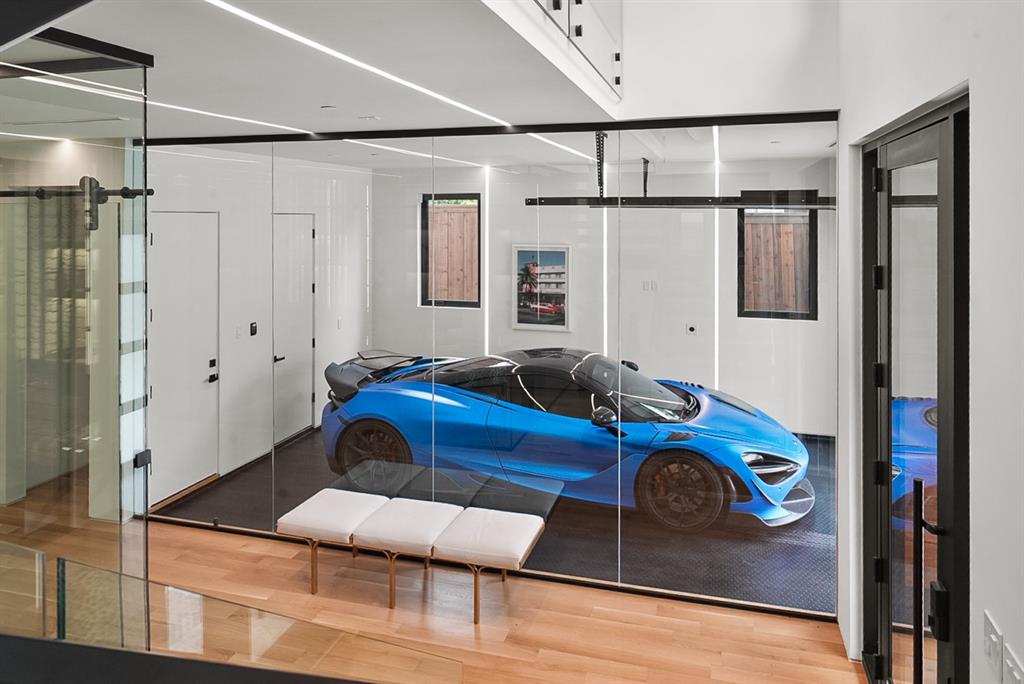 9457 Waterview Road Dallas, TX 75218 - Photo 9 of 28 Glass-enclosed showroom garage featuring track lighting, white walls, and a dark textured floor