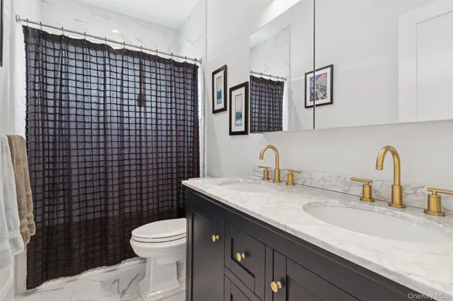 a bathroom with a granite countertop toilet sink washing machine and mirror