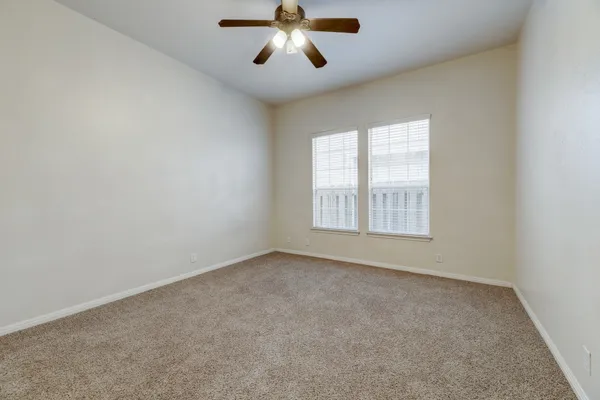 an empty room with windows and chandelier fan