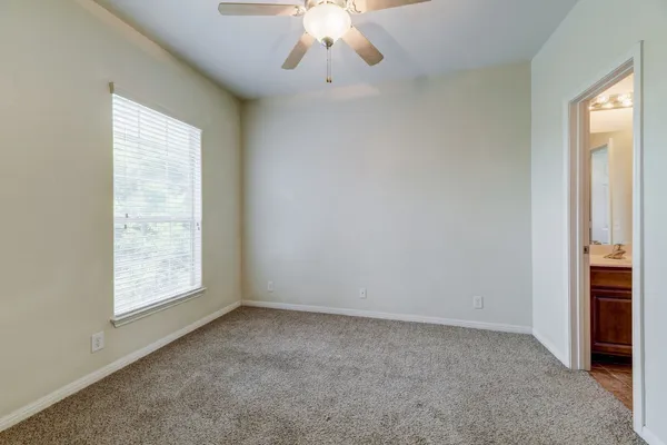 an empty room with a window and a chandelier fan