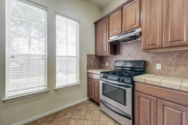 a kitchen with granite countertop a stove a sink and dishwasher wooden cabinets with a window