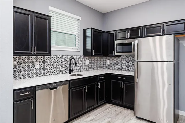 a kitchen with kitchen island granite countertop a sink stainless steel appliances and cabinets
