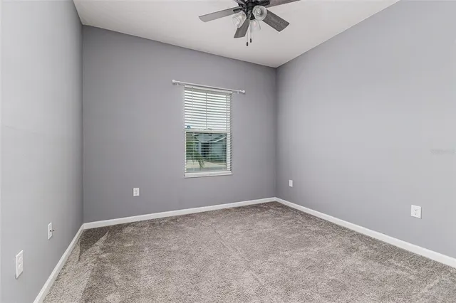 an empty room with a window and a fan
