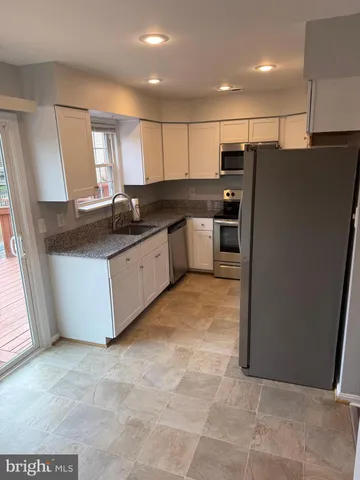 a kitchen with stainless steel appliances granite countertop a refrigerator a sink and a stove