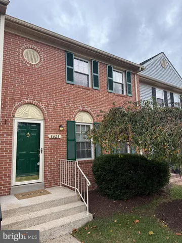 a view of a brick house with plants and large tree