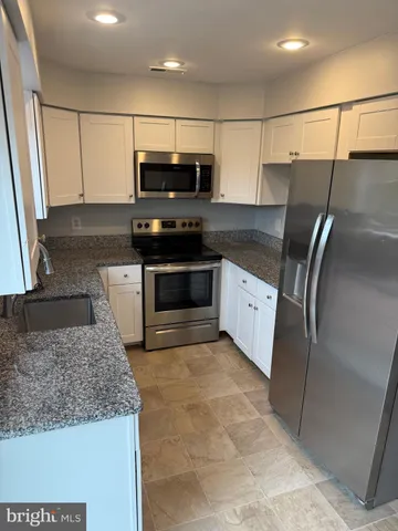 a kitchen with stainless steel appliances granite countertop a sink and a stove