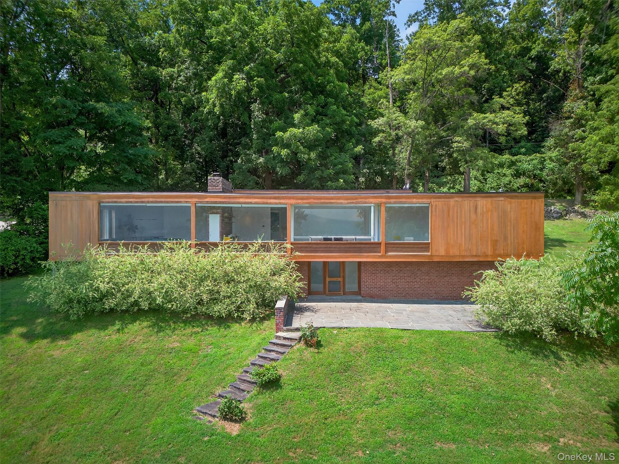 View of front of house with a front lawn, a patio area, brick siding, and a chimney