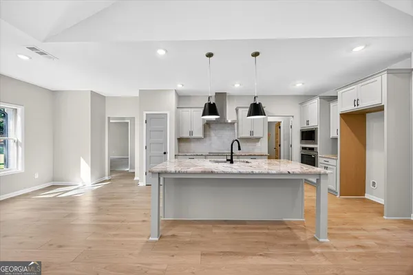 a kitchen with stainless steel appliances granite countertop a sink a stove and a wooden floors
