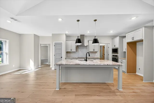 a kitchen with stainless steel appliances granite countertop a sink a stove and a wooden floors