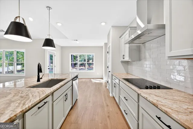 a kitchen with kitchen island stainless steel appliances a sink a counter top space stove and cabinets