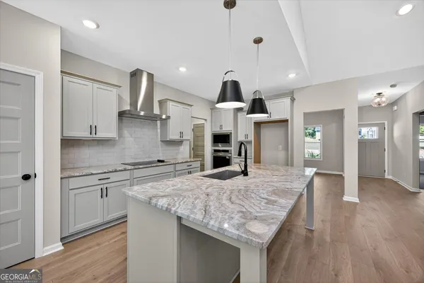 a kitchen with stainless steel appliances granite countertop hardwood floor sink stove and wooden floor