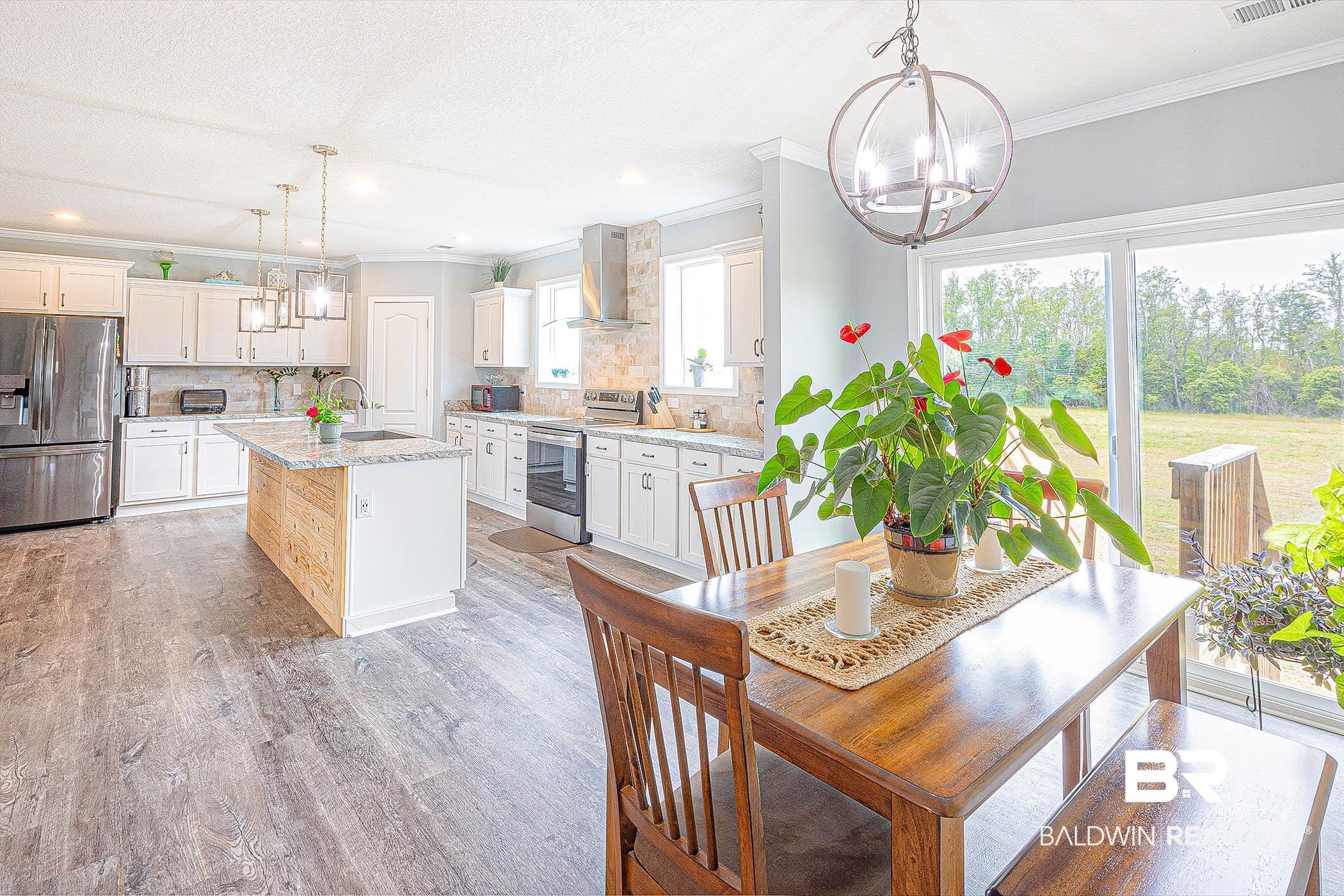 16000 John Bauer Road Summerdale, AL 36580 - Photo 17 of 34 Kitchen featuring decorative light fixtures, a center island with sink, stainless steel appliances, a sink, and wall chimney range hood