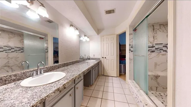 a bathroom with a granite countertop sink a mirror and a shower