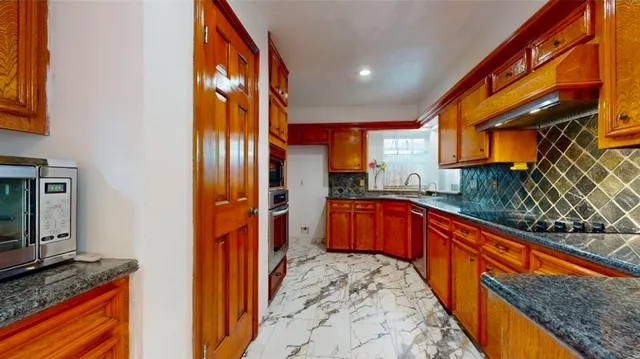a kitchen with stainless steel appliances granite countertop a refrigerator and a stove top oven