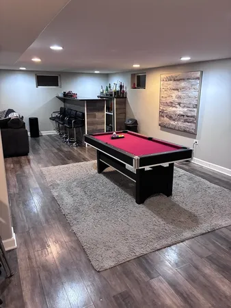 a room with pool table gym equipment wooden floor and windows