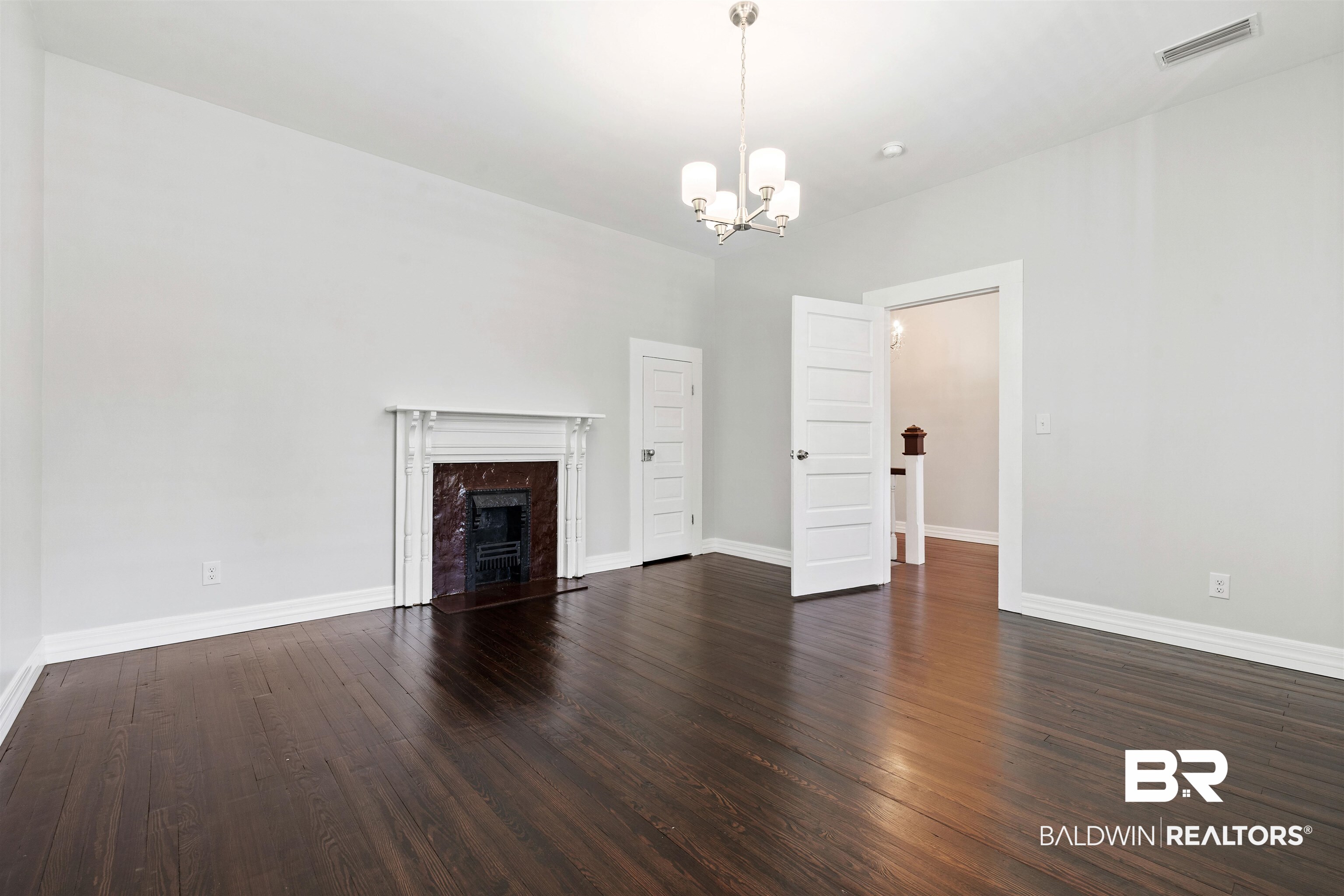 407 East 2nd Street Bay Minette, AL 36507 - Photo 16 of 40 Unfurnished living room with dark wood-type flooring, a premium fireplace, and a chandelier
