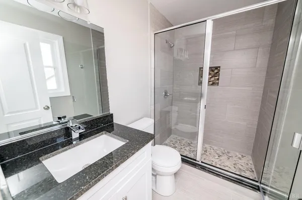 a bathroom with a granite countertop sink toilet and shower