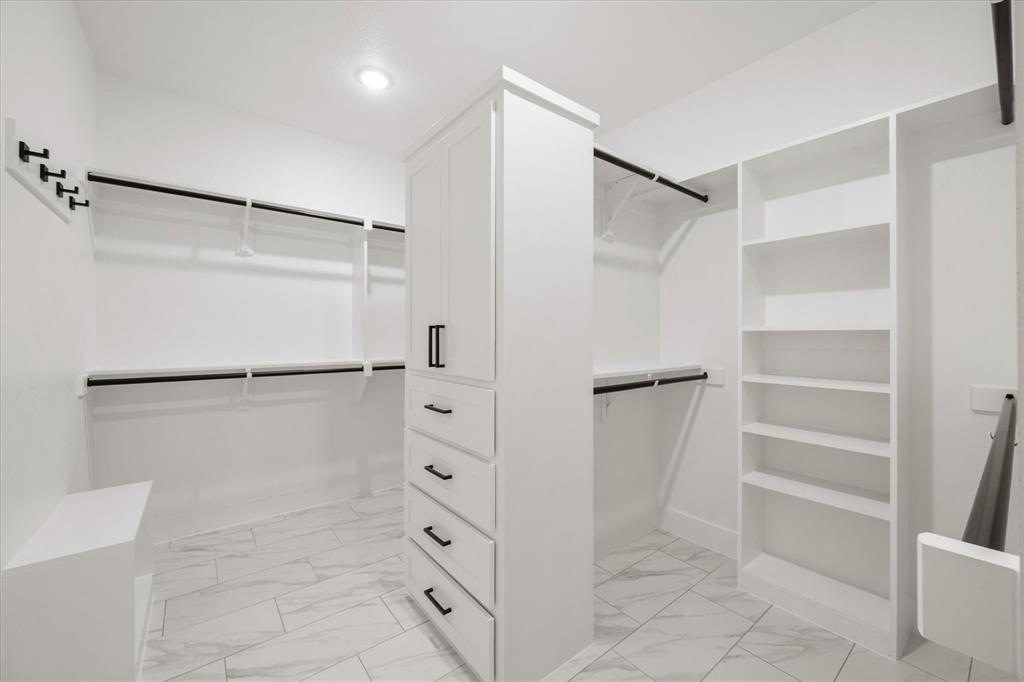 6610 Waggoner Way Midlothian, TX 76065 - Photo 24 of 40 Custom closet system featuring white cabinetry, multiple hanging rods, built-in shelving, and drawer storage