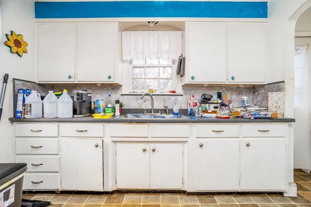 a kitchen with white cabinets and window