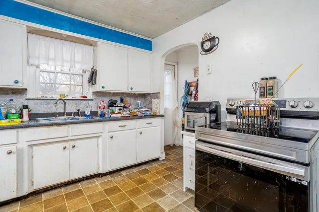 a kitchen with stainless steel appliances a stove a sink and white cabinets