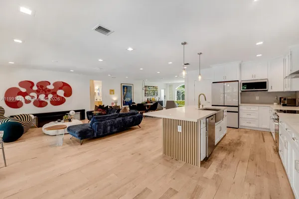 a kitchen with kitchen island granite countertop a refrigerator a stove a sink and white cabinets