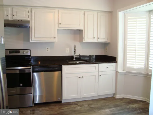 a kitchen with granite countertop white cabinets and black appliances