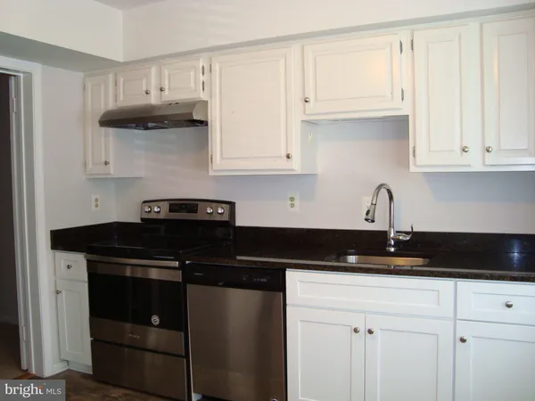 a kitchen with stainless steel appliances granite countertop white cabinets and a sink