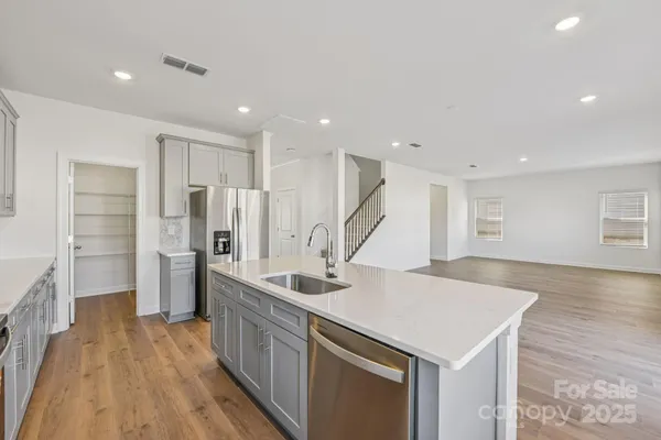a kitchen with stainless steel appliances a sink and wooden floor