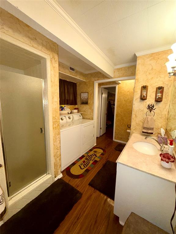 309 Broken Arrow Comanche, TX 76442 - Photo 18 of 33 Bathroom with vanity, a shower stall, wallpapered walls, washing machine and dryer, and dark wood-style floors