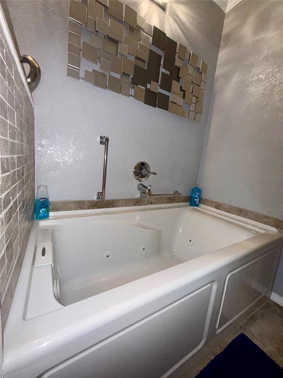 309 Broken Arrow Comanche, TX 76442 - Photo 9 of 33 Bathroom featuring a tub with jets and tile patterned flooring