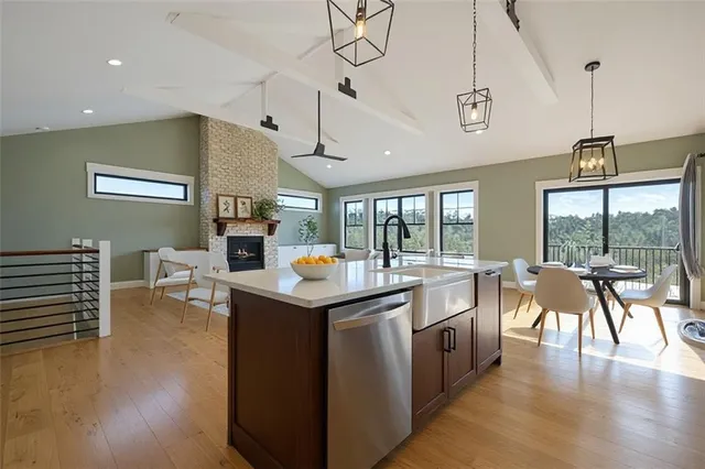 a open kitchen with stainless steel appliances granite countertop a stove top oven a dining table and chairs with wooden floor