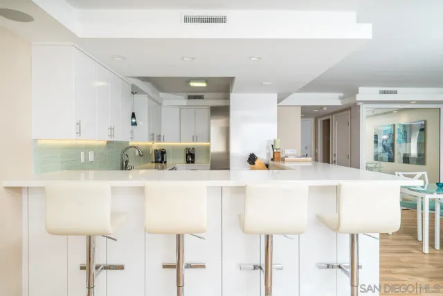 a white kitchen with cabinets and chairs