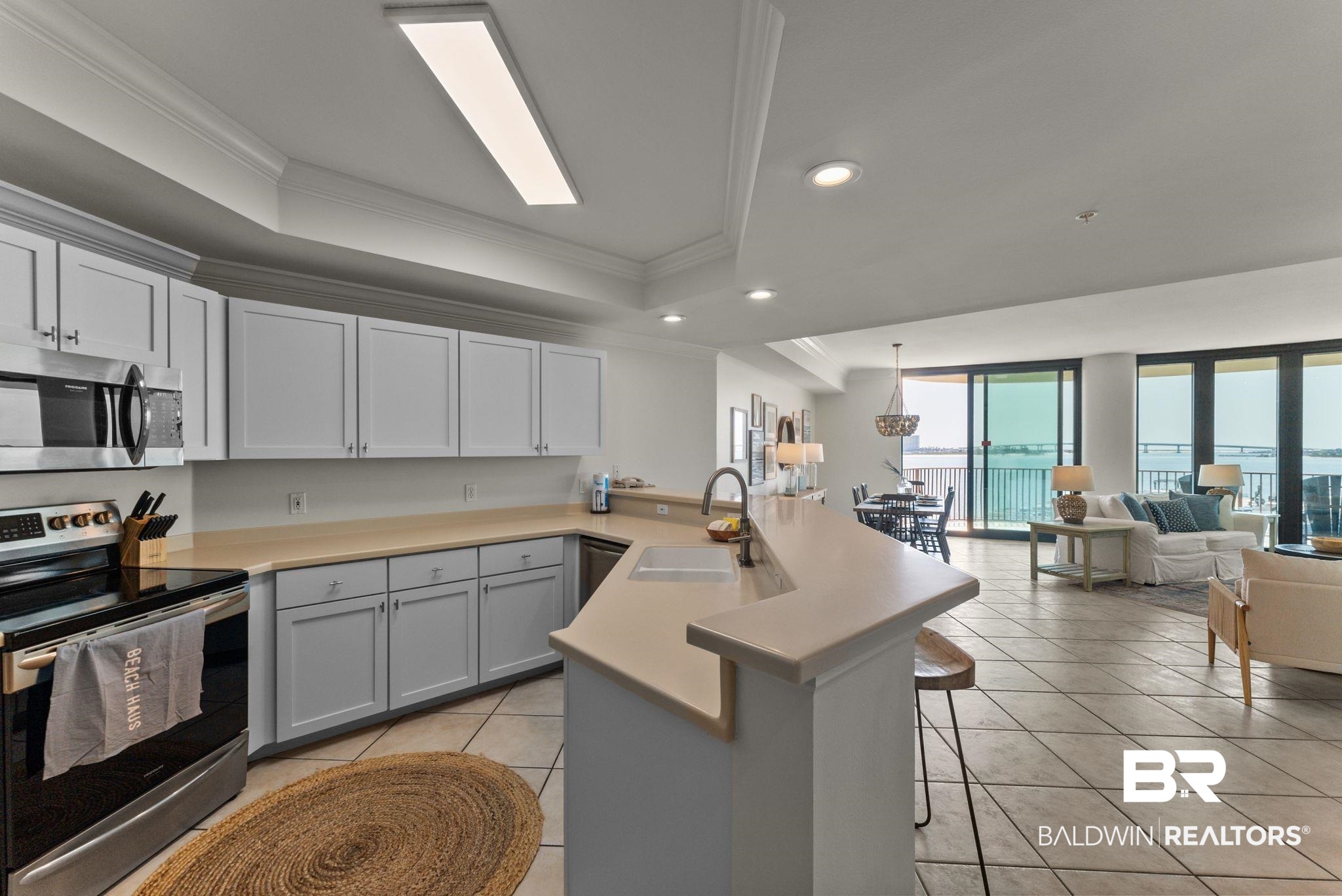 27580 Canal Road, Unit 1233 Orange Beach, AL 36561 - Photo 35 of 79 Kitchen with a peninsula, stainless steel appliances, a breakfast bar area, light countertops, and a tray ceiling
