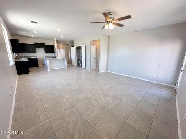 a view of a livingroom with a ceiling fan furniture and kitchen view