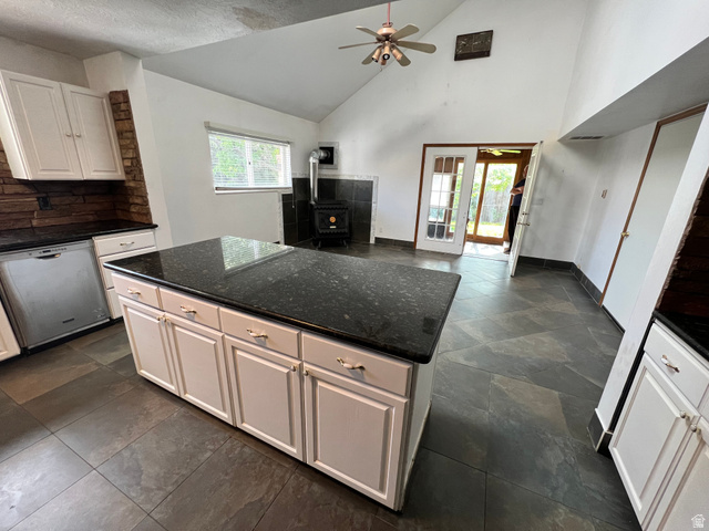 3013 North 100 West Provo, UT 84604 - Photo 9 of 18 Kitchen featuring a wood stove, a kitchen island, dishwasher, ceiling fan, and dark stone counters