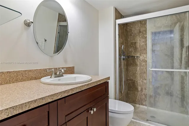 a bathroom with a granite countertop sink toilet a mirror and shower