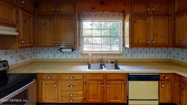 an empty room with a chandelier fan and a window