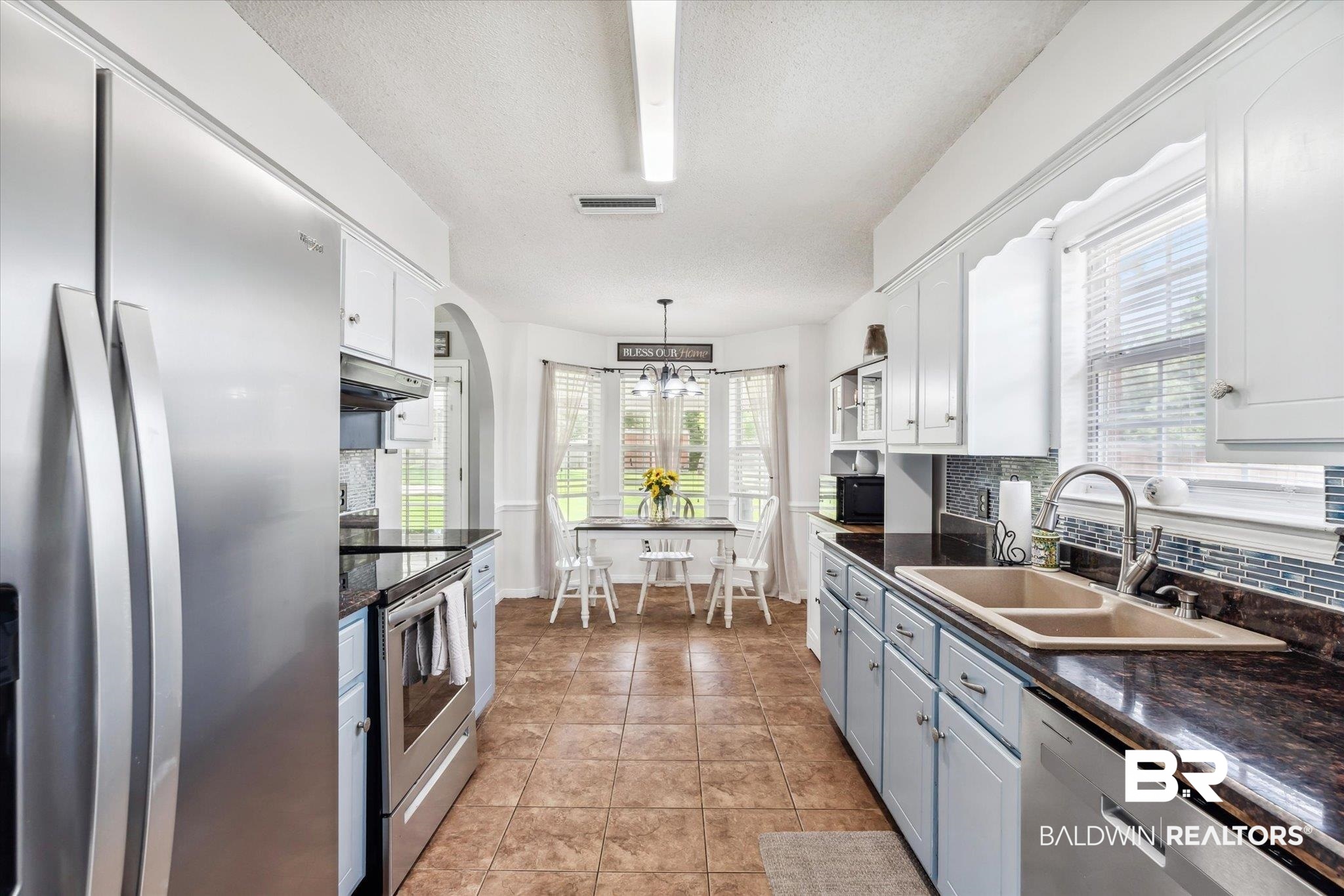 9306 Prairie Drive Semmes, AL 36575 - Photo 6 of 20 Kitchen with white cabinetry, light tile patterned floors, stainless steel appliances, hanging light fixtures, and sink