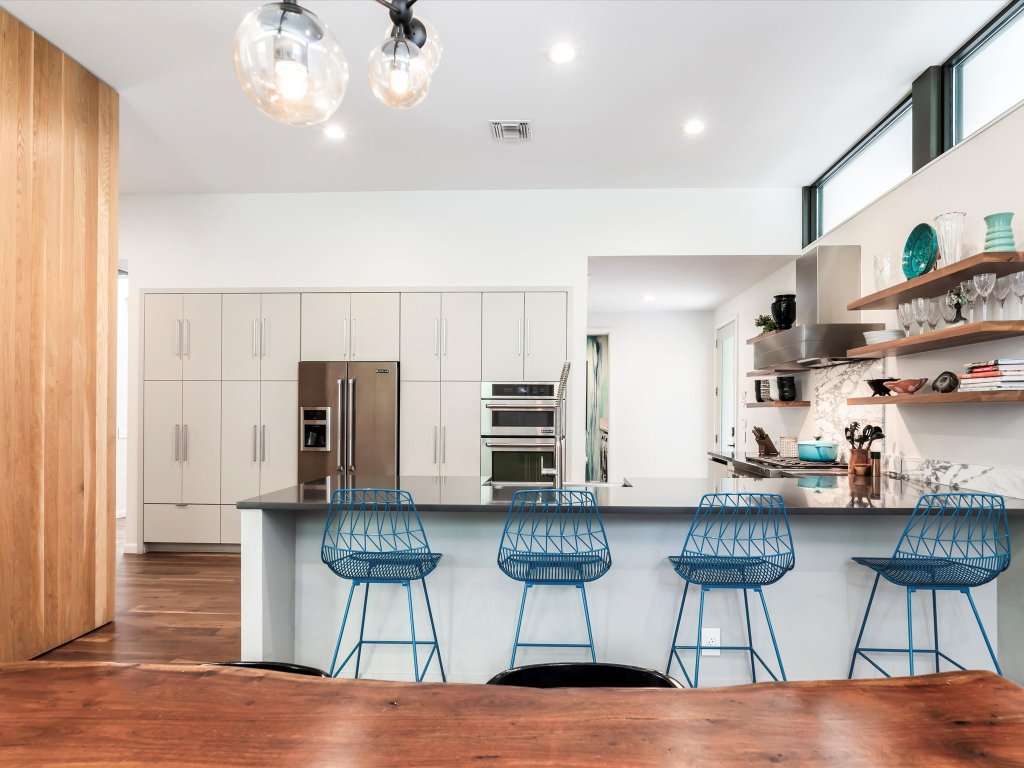 1703 Dexter Street Austin, TX 78704 - Photo 3 of 34 Kitchen featuring a peninsula, appliances with stainless steel finishes, open shelves, wall chimney exhaust hood, and white cabinetry