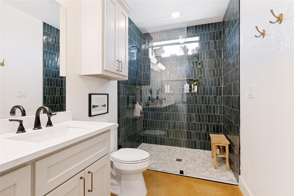 490 Private Road 4512 Decatur, TX 76234 - Photo 15 of 27 Bathroom featuring a walk-in shower with dark emerald subway tile, a white vanity with quartz countertop, dual matte black faucets, and a built-in wall cabinet