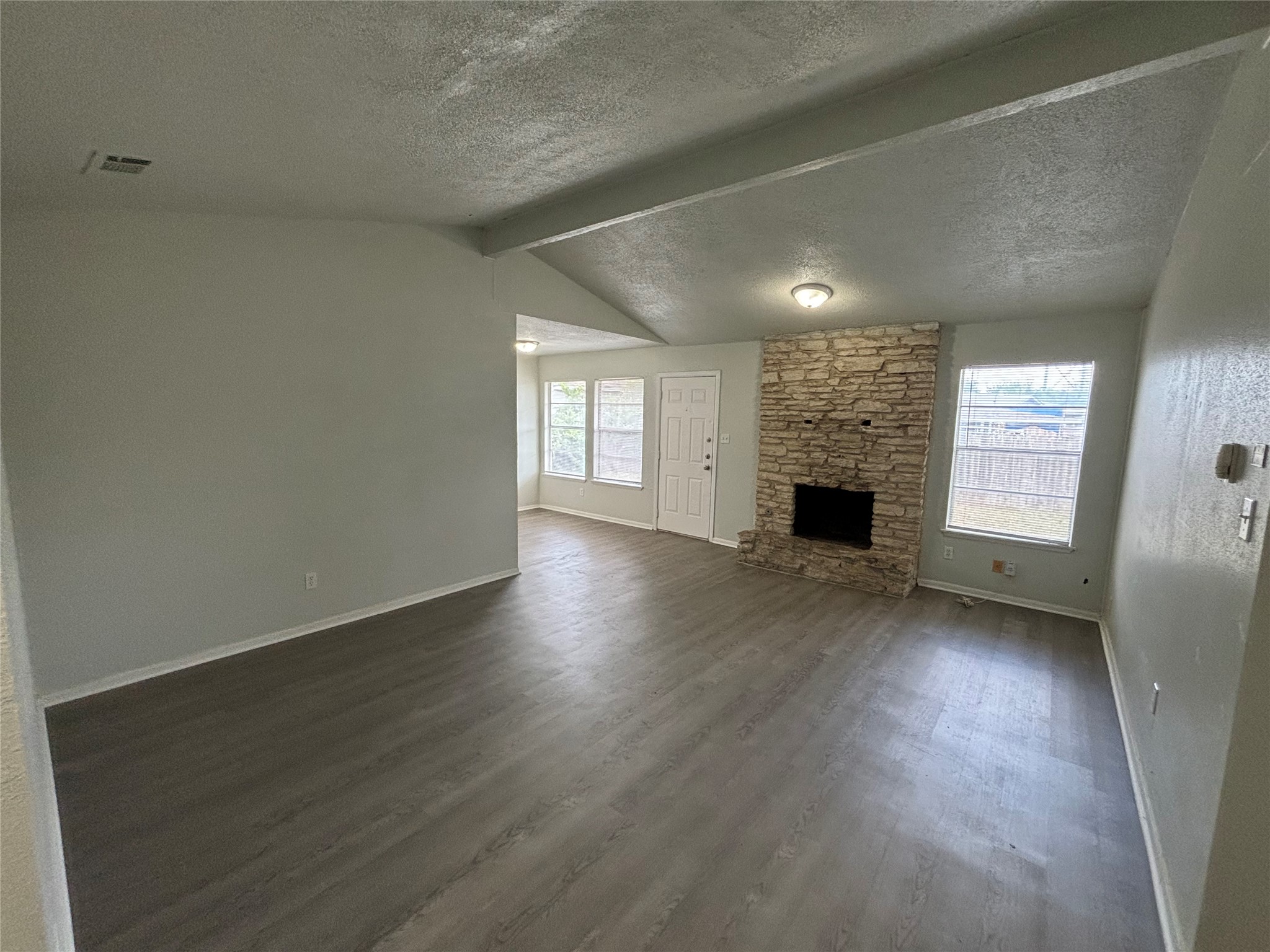 5905 Cherry Loop Austin, TX 78745 - Photo 2 of 13 A spacious living area features vaulted ceilings, durable wood flooring, and a stone-clad fireplace.